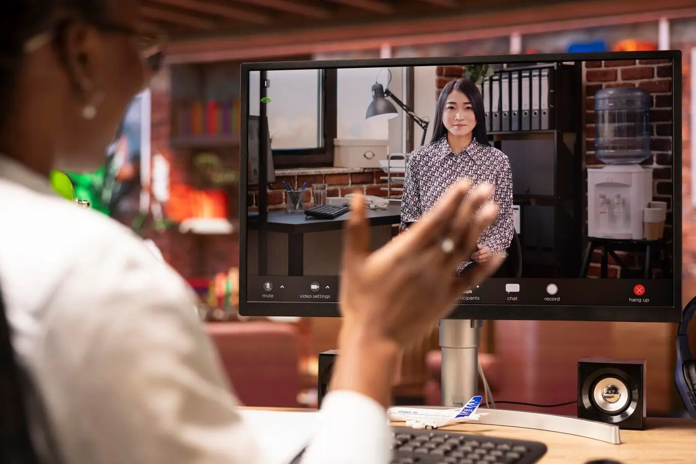 Close-up of a woman greeting an HR representative during a video call interview on a PC.